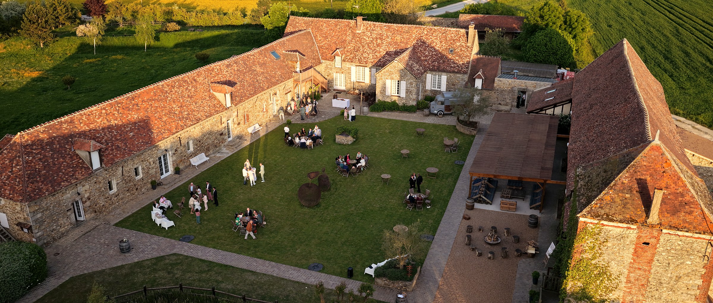 Vue aérienne d'un domaine en pierre au coucher de soleil, cour intérieure et invités