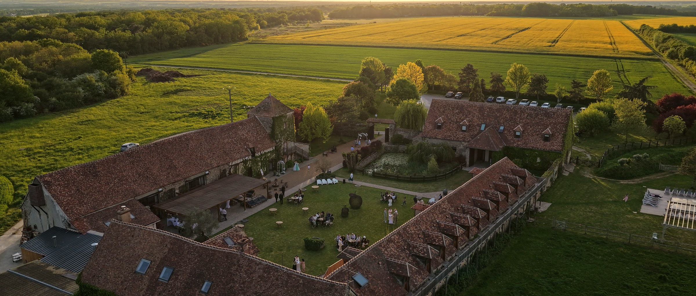 Vue aérienne large de la longère et des champs de colza alentour